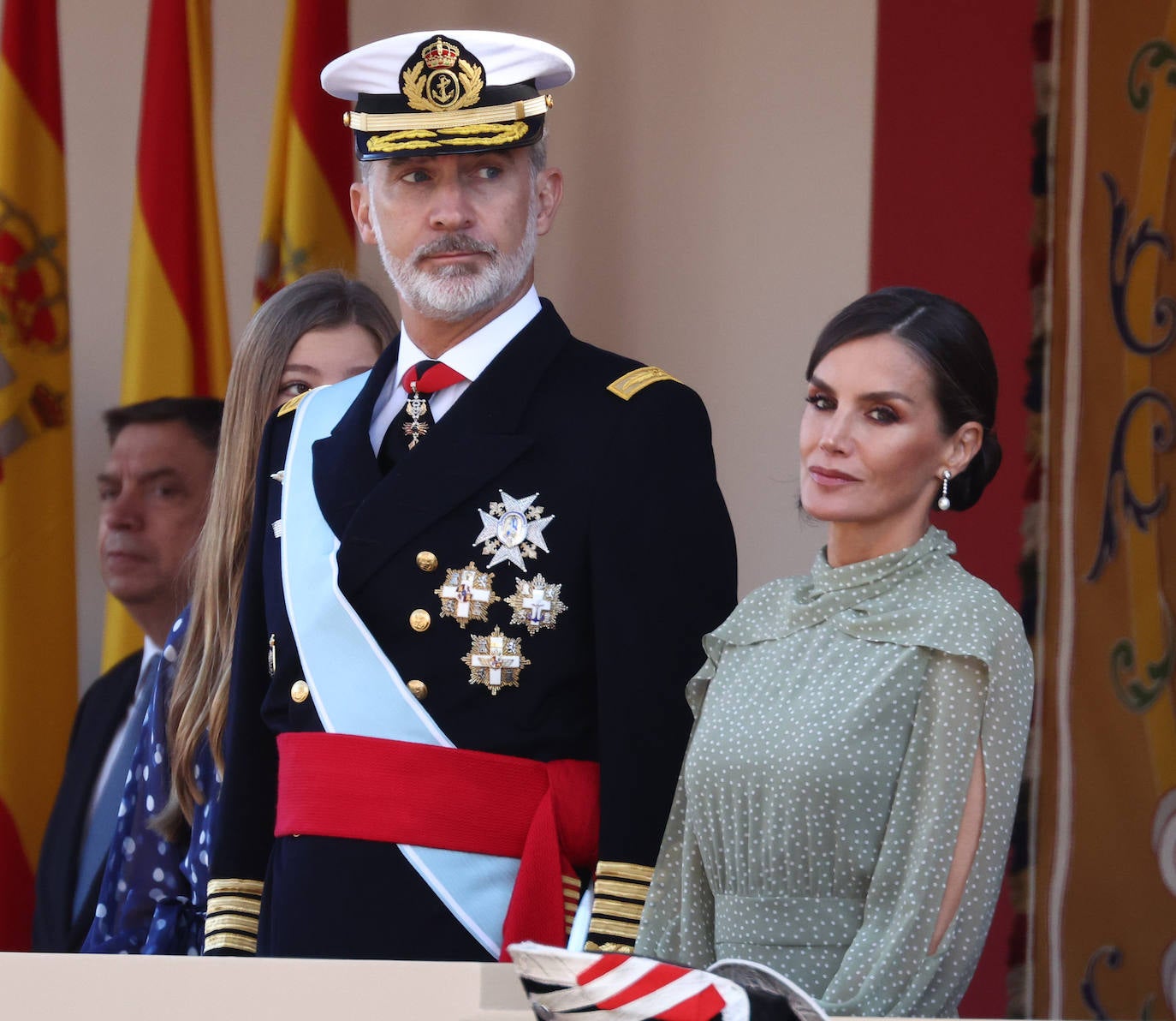 La reina opta por un vestido de gasa en verde con lunares blancos de la firma española Vogana. Se trata del modelo Nanda, de la colección del año 2021, con un precio de 265 euros. En la pieza de silueta fluida y cintura marcada destacaban las originales mangas, con una abertura que dejaba ver discretamente sus torneados brazos y formadan una suerte de capa. Menos discretos son los espectaculares pendientes de perlas australianas que le regaló don Felipe hace más de una década, con los que completó el estilismo.