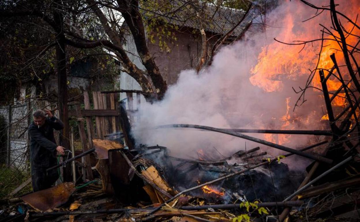 Un hombre intenta evitar la destrucción total de su casa en una localidad ucraniana bormardeada por la artillería rusa.