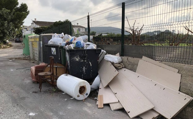 Muebles, maderas y un termo  tirados junto a los contenedores cerca de la rotonda de entrada a Dénia. 