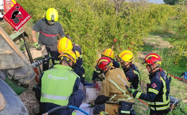 Los bomberos liberan al hombre atrapado debajo del tractor. 