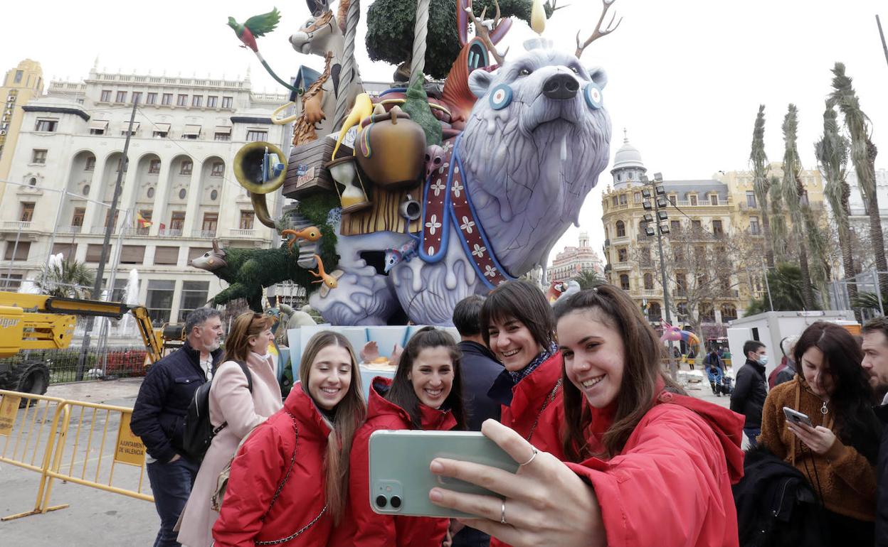 Un grupo de falleras se fotografía junto a una falla en Valencia. 