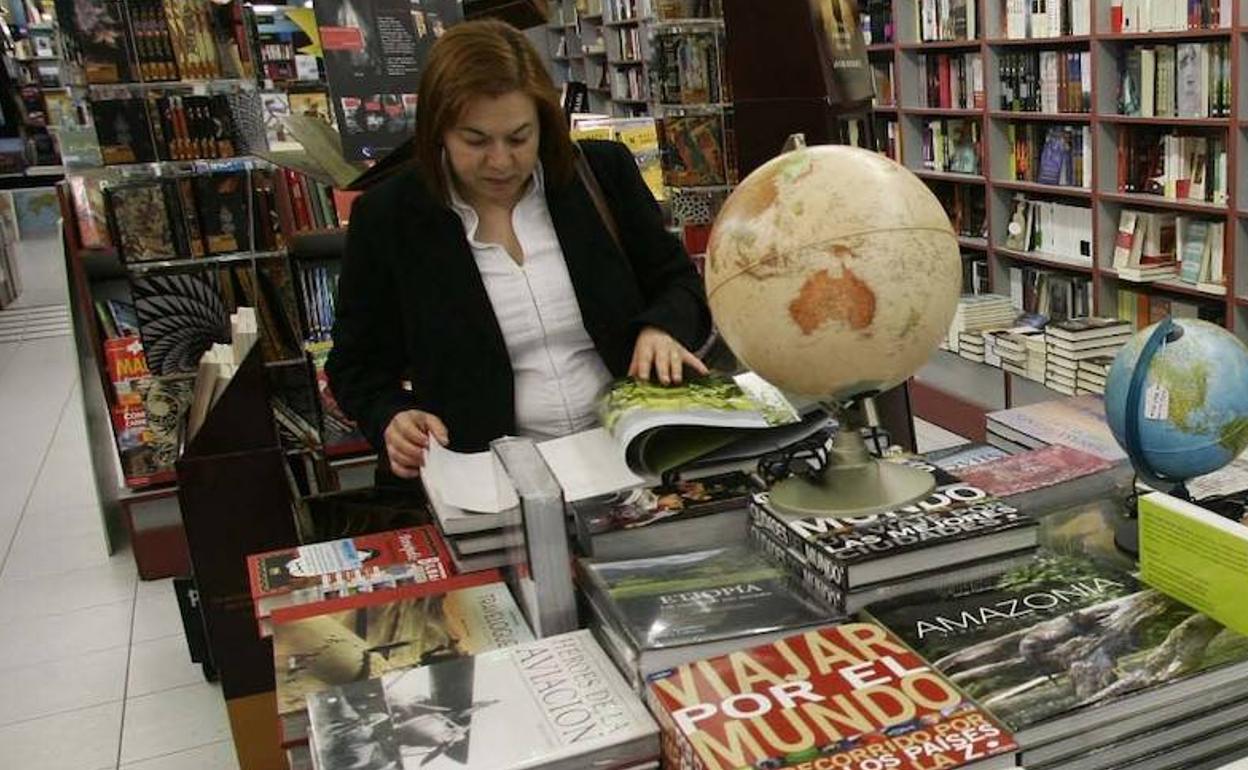 Una mujer consulta un volumen en una librería. 