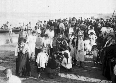 Imagen secundaria 1 - Imágenes del regreso de los pescadores a la playa del Cabanyal y mujeres y niños observando el pescado. 