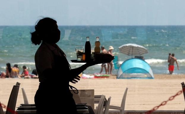 Una camarera sirve bebidas en un local de playa. 