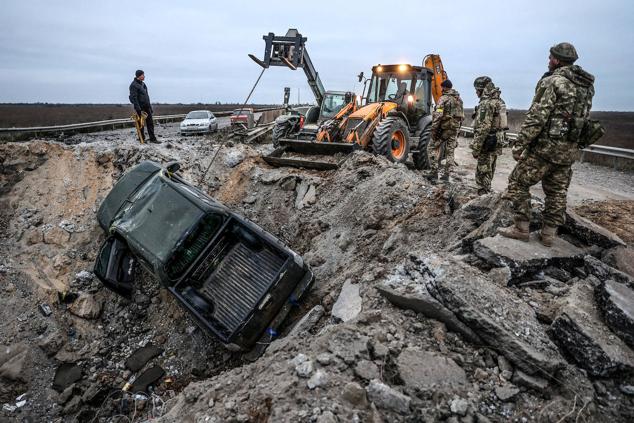 Soldados ucranianos sacan un coche de un cráter en la carretera en la región de Kherson el 13 de noviembre de 2022.