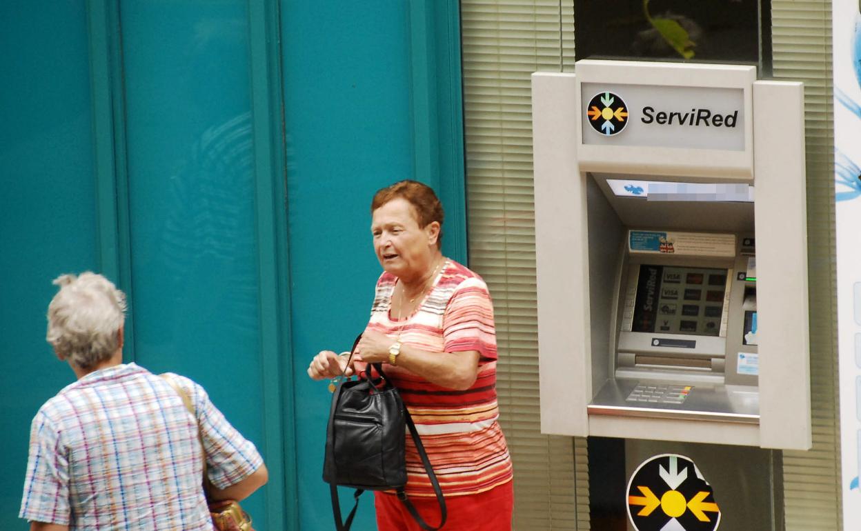 Una mujer guarda su bolso tras utilizar un cajero automático.