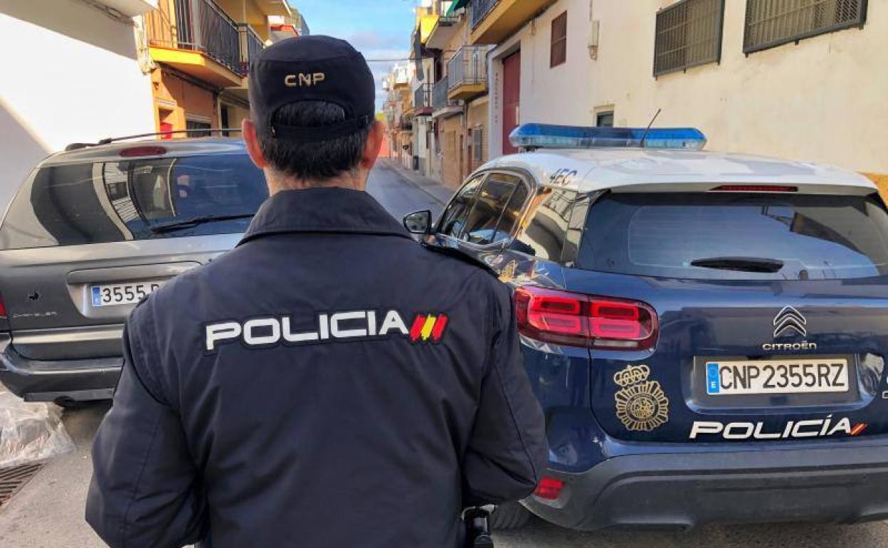 Un agente de la Policía Nacional frente al coche patrulla. 