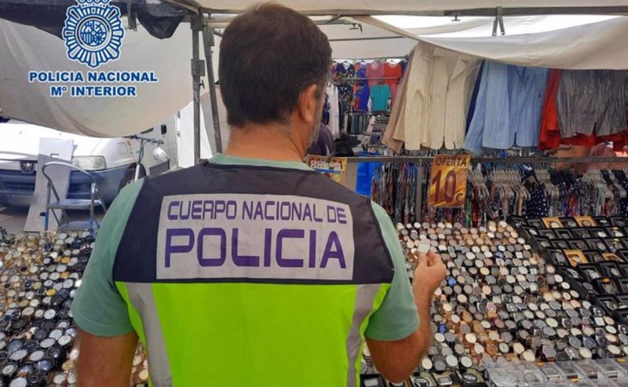 Un agente comprueba los relojes en el mercadillo. 