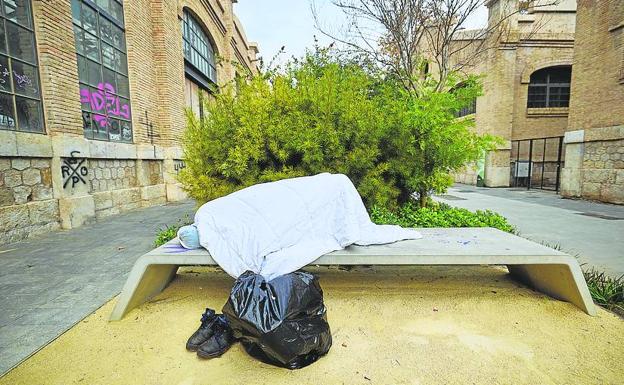 Una persona se refugia en un banco del parque. 