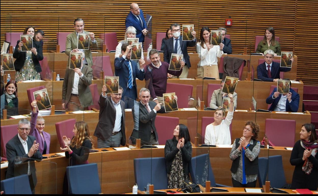 Los diputados del PP muestran una imagen de Ximo Puig y Pepe Cataluña juntos, en el hemiciclo de Les Corts. 