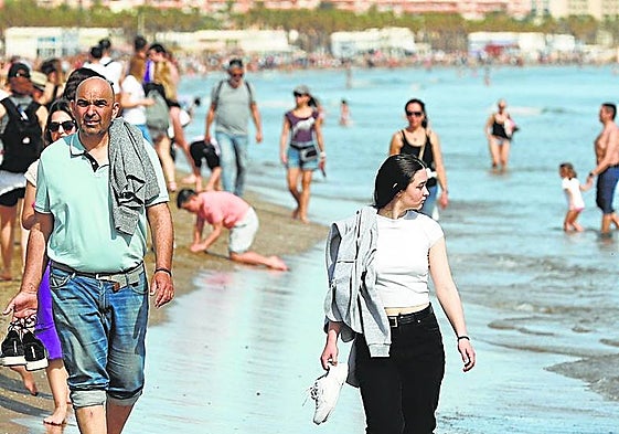 Personas pasean por la orilla de la playa
