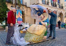 Dos artistas desembalan un ninot de la Falla Mercat de Gandia.