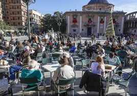 Mesas repletas de turistas en la plaza de la Virgen de Valencia.