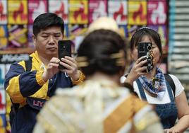 Unos turistas fotografiando a una joven vestida de valenciana.