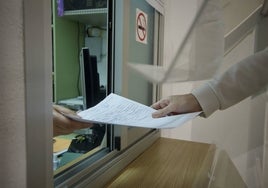 Un padre presentando documentación en la secretaría de un centro.