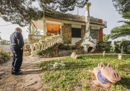 Un cerdo de trencadís da la espalda a Mario 'Albi' en el jardín de 'La Chacra', junto a una antigua chimenea transformada caprichosamente en caseta para perro.