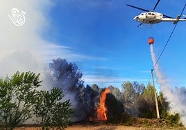 El helicóptero descargando agua sobre el fuego.