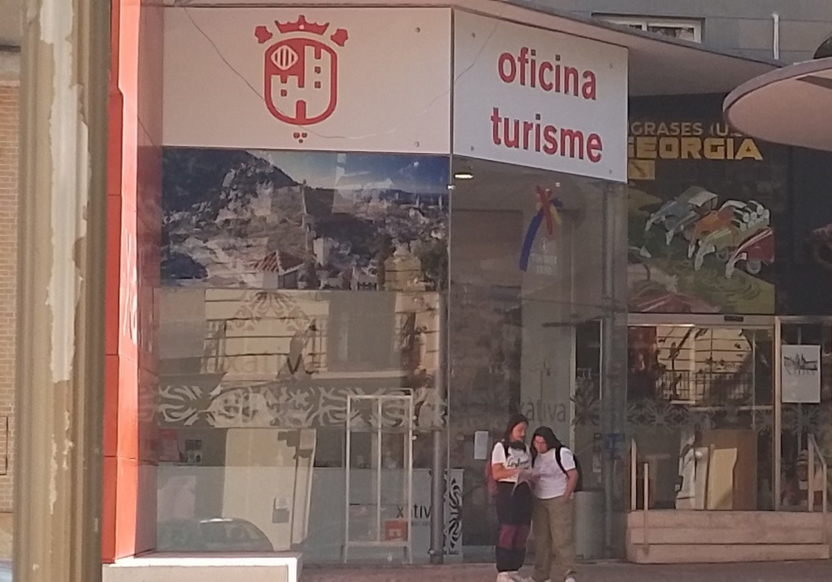 Dos turistas en la puerta de la Oficina de Turismo de Xàtiva.