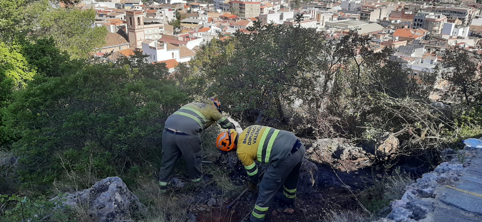 Dos brigadistas apagan los últimos rescoldos del fuego de Villalonga.