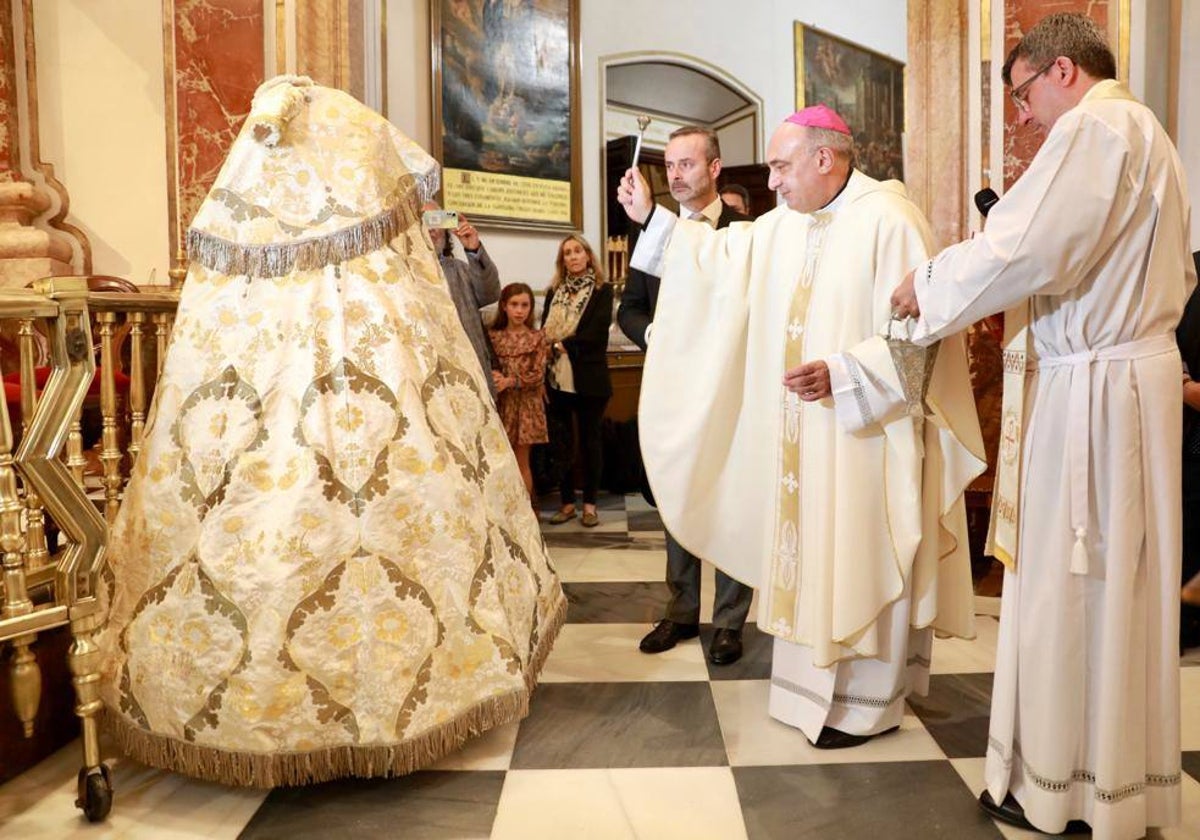 El arzobispo de Valencia, Enrique Benavent, bendice el manto obsequiado por el Gremio de Sastres, ante la antenta mirada del rector de la Basílica, Melchor Seguí.