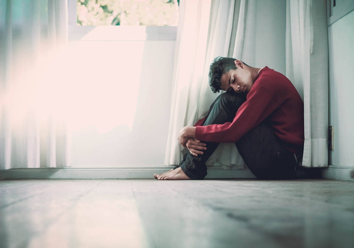 Un joven sentado en el rincón de una habitación.