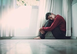 Un joven sentado en el rincón de una habitación.