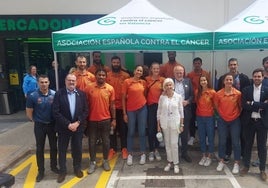 El Valencia Basket posa junto a la mesa petitoria presidida por Hortensia Herrero.