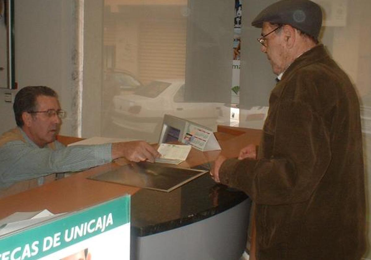 Pensionistas con una cartilla de ahorro en el banco, en una imagen de archivo.