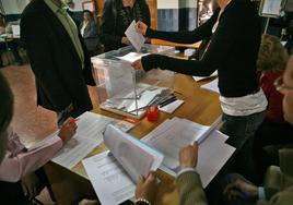 Interventores en un colegio electoral comprueban la identificación de un elector, imagen de archivo.