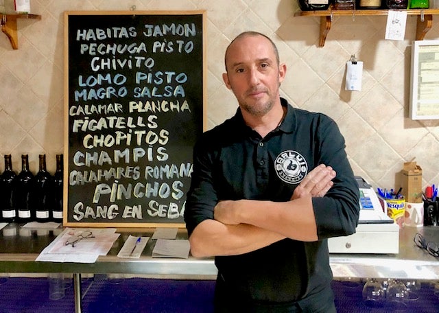 Imagen principal - Morell junto a la pizarra de tapas; el bocadillo de figatells con cebolla caramelizada y la tapa de callos que guisan con almendras y guindillla. 