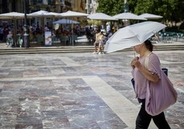 Una mujer se resguarda del calor con un paraguas en el centro de Valencia.