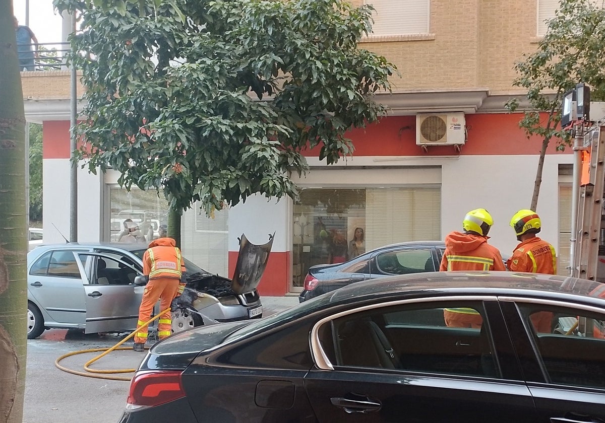 Uno de los bomberos refresca el vehículo tras sofocar el fuego.