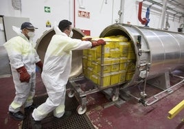 Dos operarios introducen los envases con residuos en una autoclave para su desinfección.