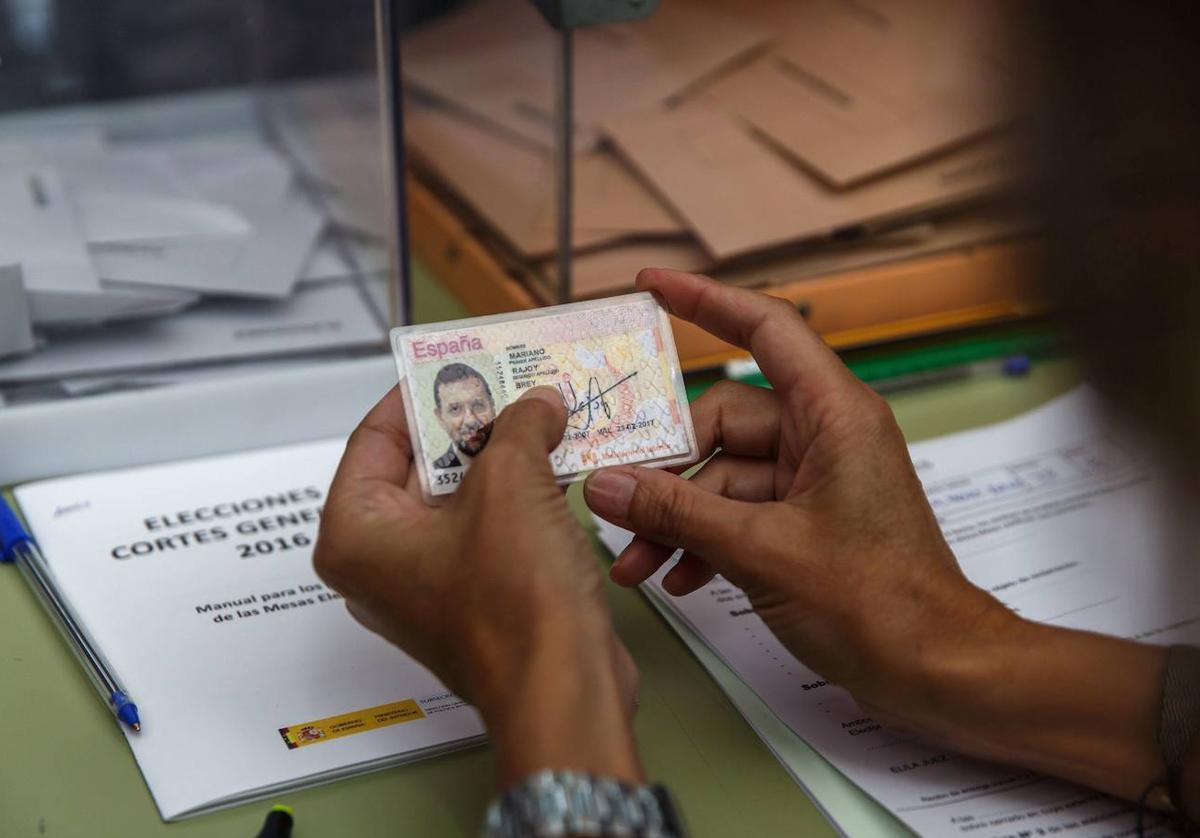 Una mujer, miembro de una mesa electoral, revisa un DNI.