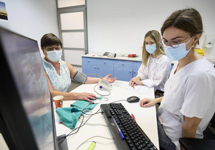 Imagen principal - Personal sanitario del Centro de Transfusión de Sangre de la Comunitat Valenciana realizando las pruebas pertinetes a un donante antes de la extración y Rita Fuster y Alfonso Barreña, donantes de sangre.