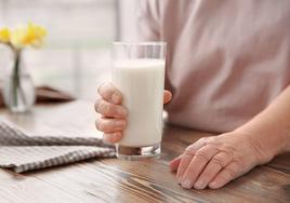 Una mujer sostiene un vaso de leche.