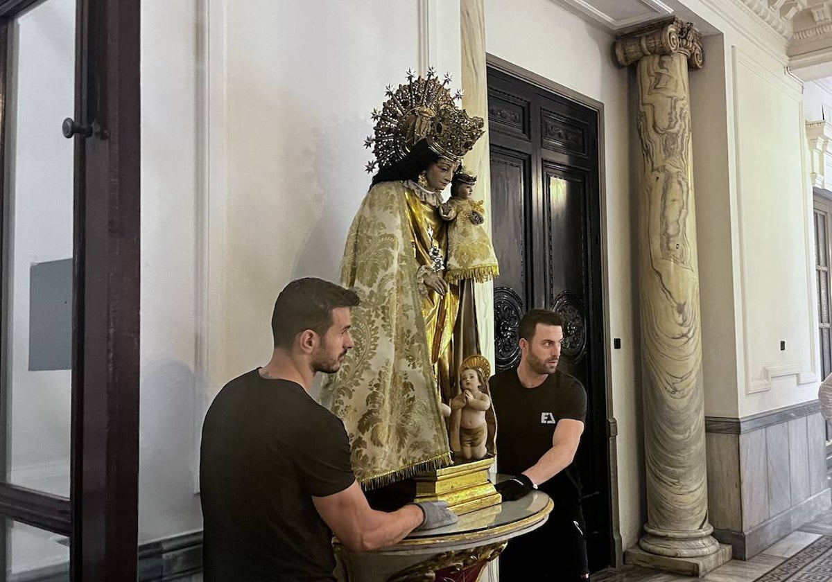 Dos operarios colocan la talla junto a la entrada a la sala de juntas, en el primer piso.