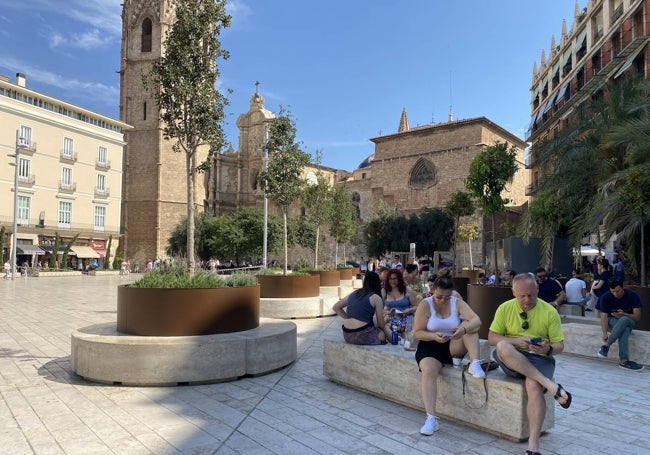 Turistas buscan sombra en un lateral de la plaza de la Reina.