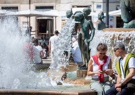 Dos personas sentadas junto a una fuente en Valencia.