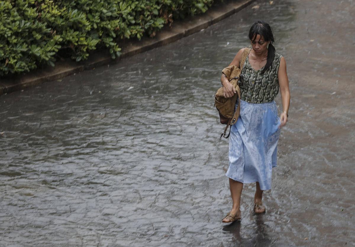 Una mujer camina en una calle con bolas de granizo.