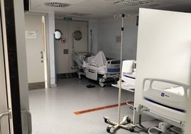 Una cama, con un paciente, junto a una salida de emergencia en el Hospital Clínico de Valencia.