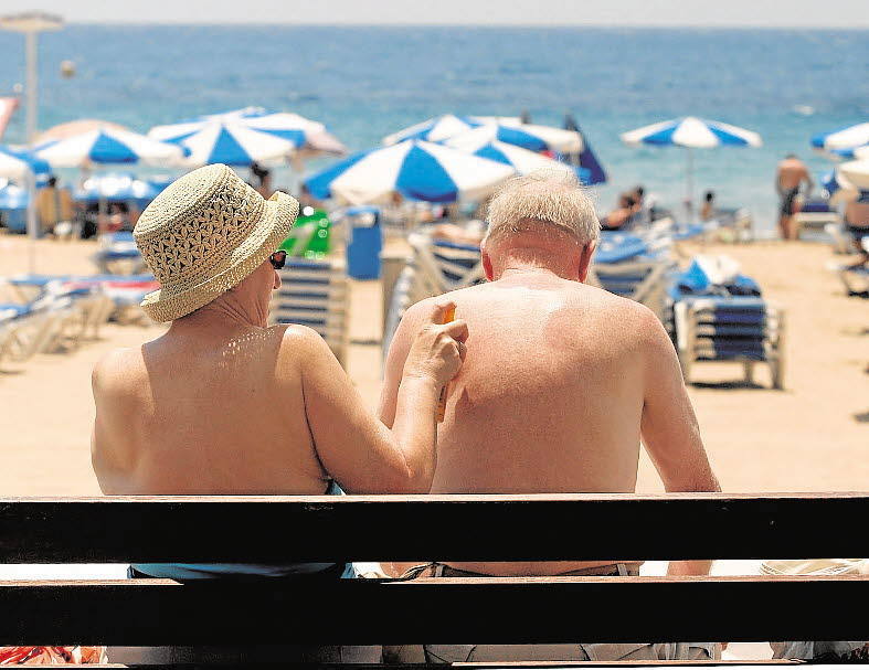 Mujer y hombre se embadurnan de protector solar en la playa