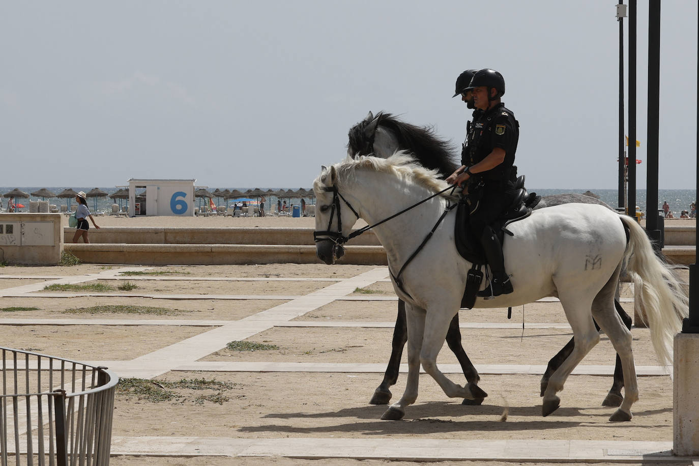 Dos agentes a caballo patrullan en la playa de Las Arenas de Valencia.