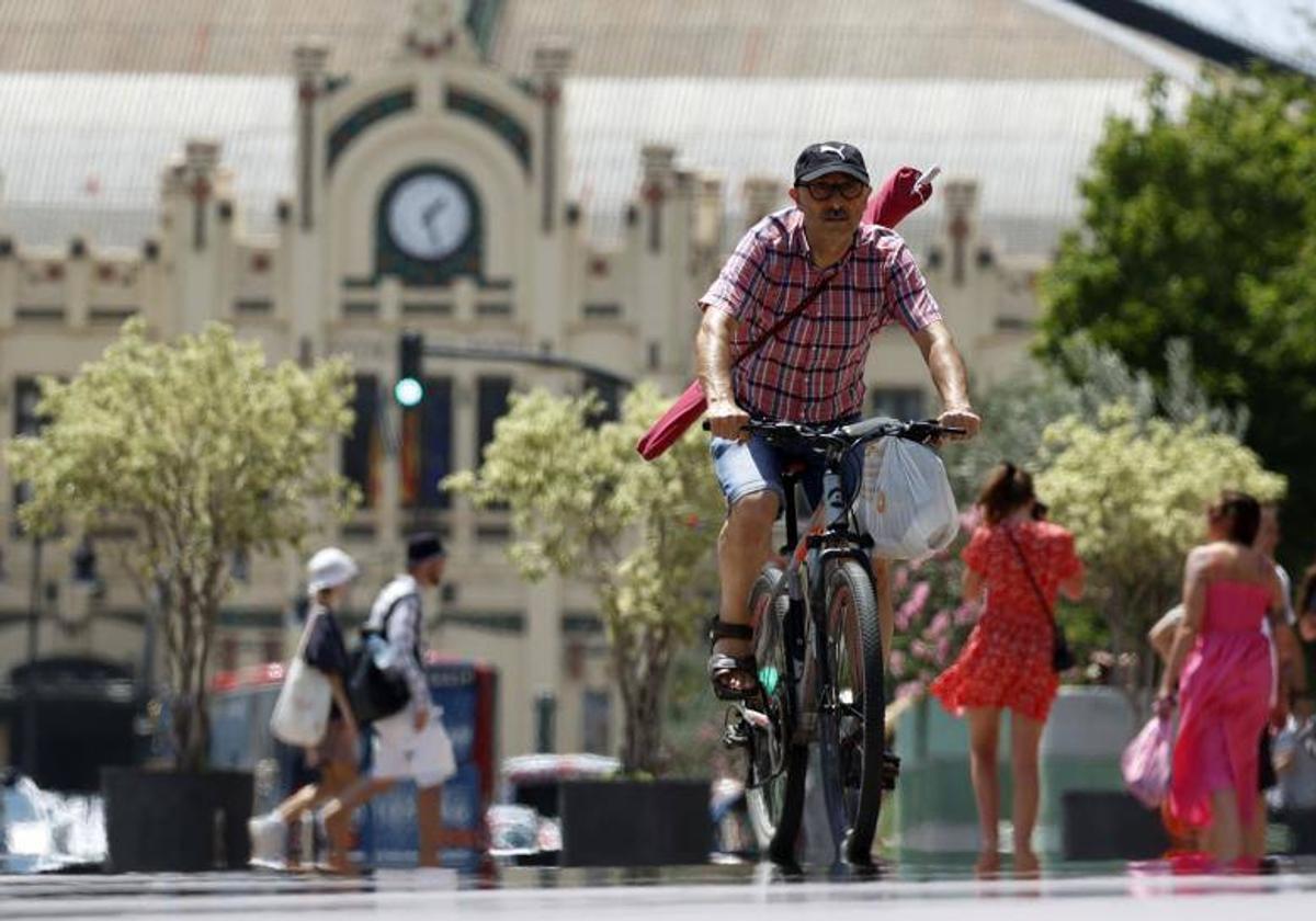 Un hombre va en bicicleta por el centro de Valencia.