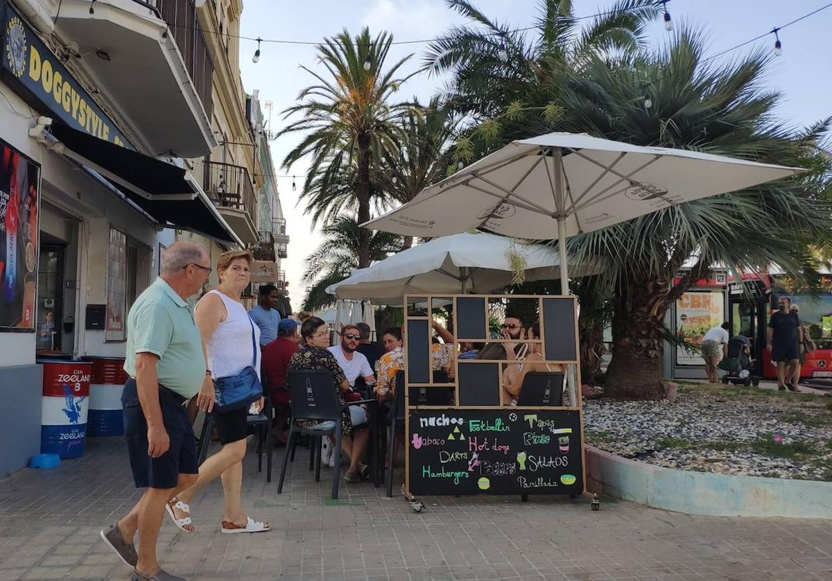 Una pareja de peatones cruza por delante de uno de los bares con terraza en la calle Eugenia Viñes.