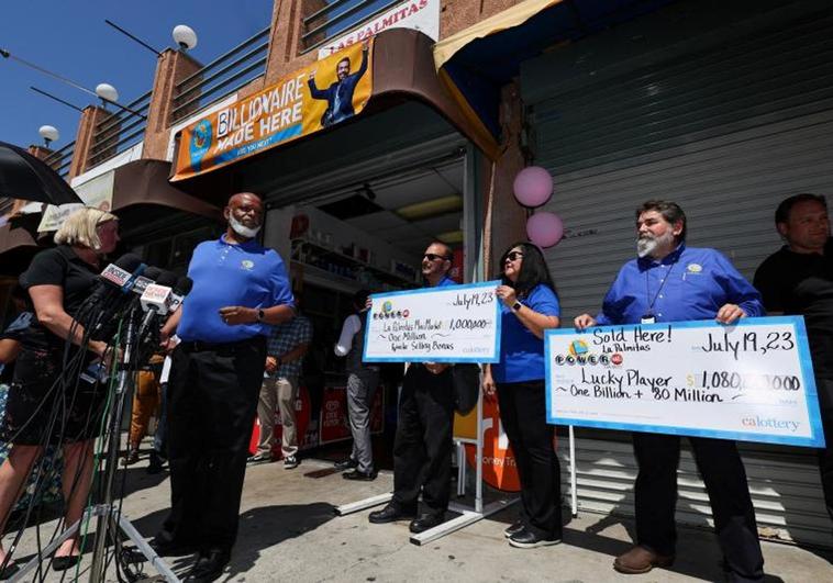 Empleados d ela tienda, con los simbólicos cheques para el desconocido billonario.