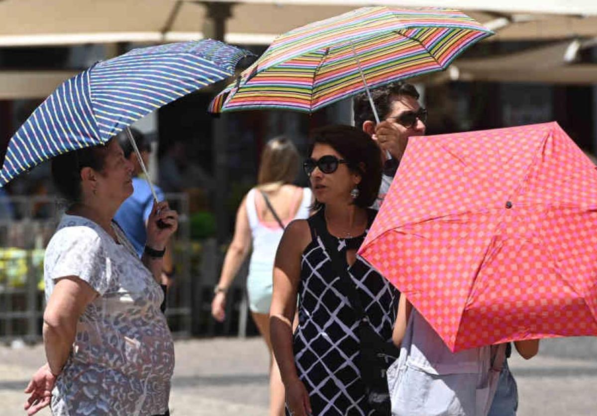 Ciudadanos se protegen del sol con paraguas.