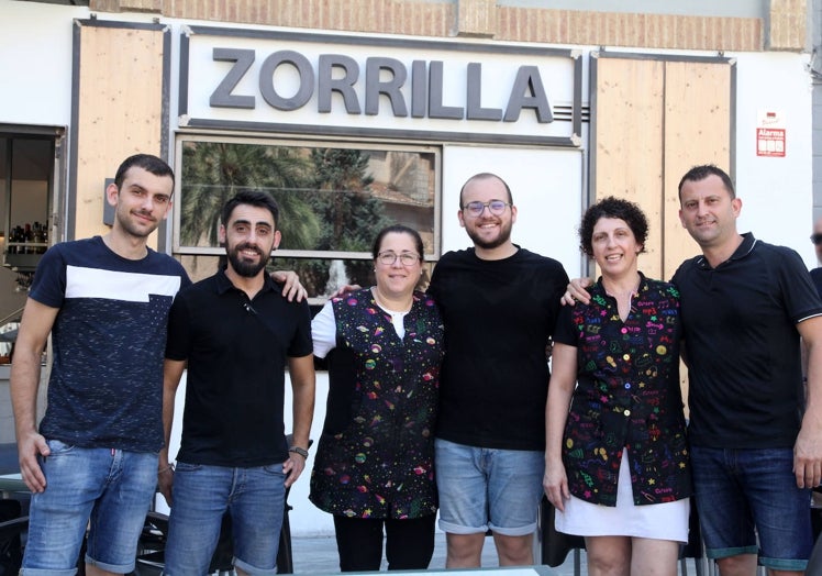 Imagen principal - La familia y el personal del bar Zorrilla, el bocadillo de sepia con Musa y una variación del 'Marjal de Pego'. 