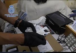 Un agente de la Policía Nacional manipula los dispositivos que utilizaban los estafadores para lograr las claves secretas de las víctimas.