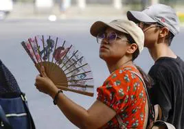 Una mujer se abanica en la calle durante la ola de calor.